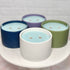 Four candles in different colored holders on a white surface